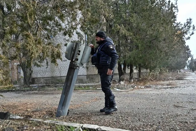 Police officer examines Russian rocket shell remains in Orikhiv Ukraine
