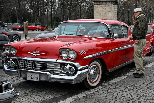 Man smoking next to classic Chevrolet at vintage car parade in Paris January 2025