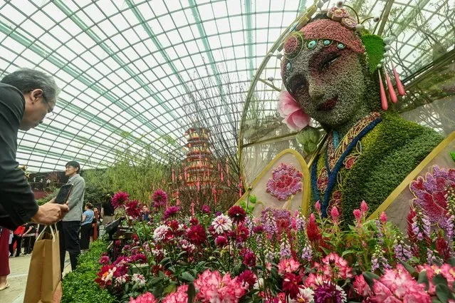 Visitor photographs Madam White Snake floral sculpture at Gardens by the Bay Singapore
