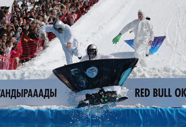 Costumed participant jumping into icy water at Red Bull Jump and Freeze Almaty Kazakhstan