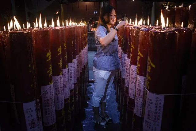 Woman lighting prayer candle at Darma Ramsi Temple for Lunar New Year Bandung Indonesia