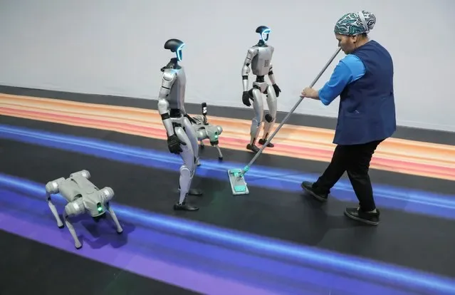 Staff cleaning floor beside robots at Digital Almaty 2025 forum in Kazakhstan
